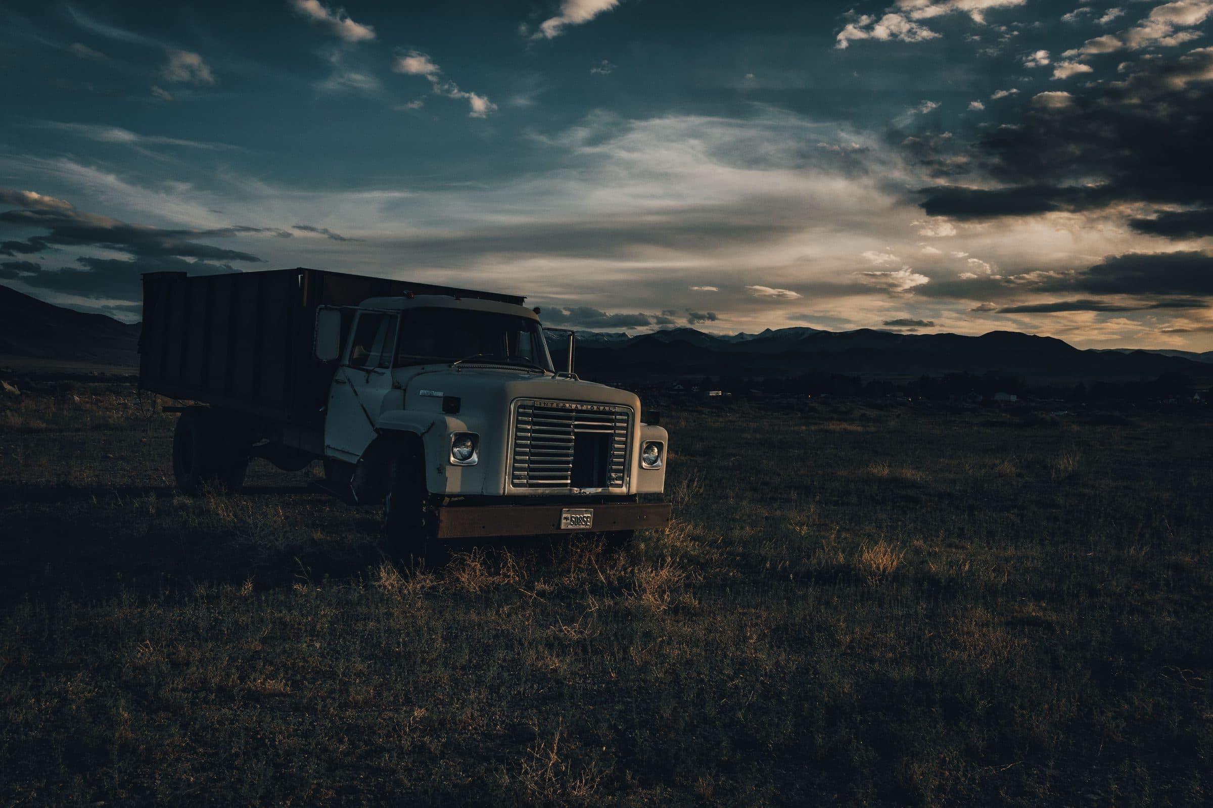 A dump truck parked in an open field at dusk